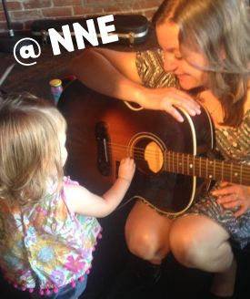 Photo of Linda with a guitar and a toddler