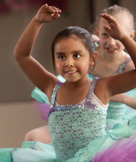 girl in green and purple ballet costume, arms raised