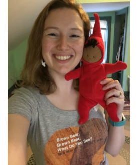 woman wearing "brown bear, brown bear, what do you see?" t-shirt holds a doll of peter from "the snowy day" to her face