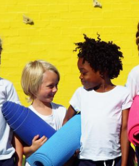 two children holding yoga mats